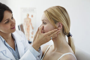 Doctor evaluating woman’s nose for rhinopasty consultation