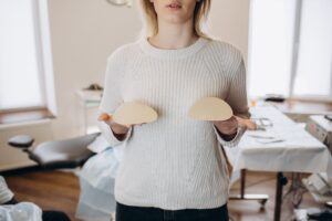 Woman holding up breast implants in front of her chest to show that she’s considering breast augmentation